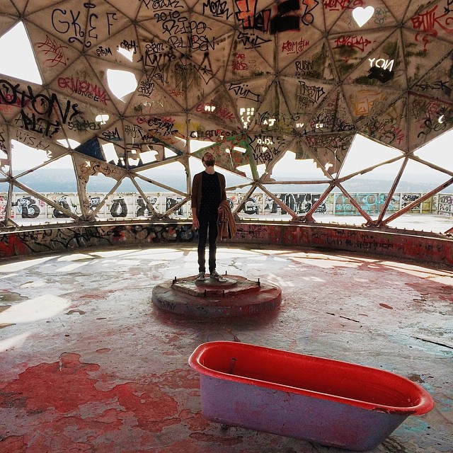 Roel standing in an abandoned listening dome with a bath tub on Teufelsberg